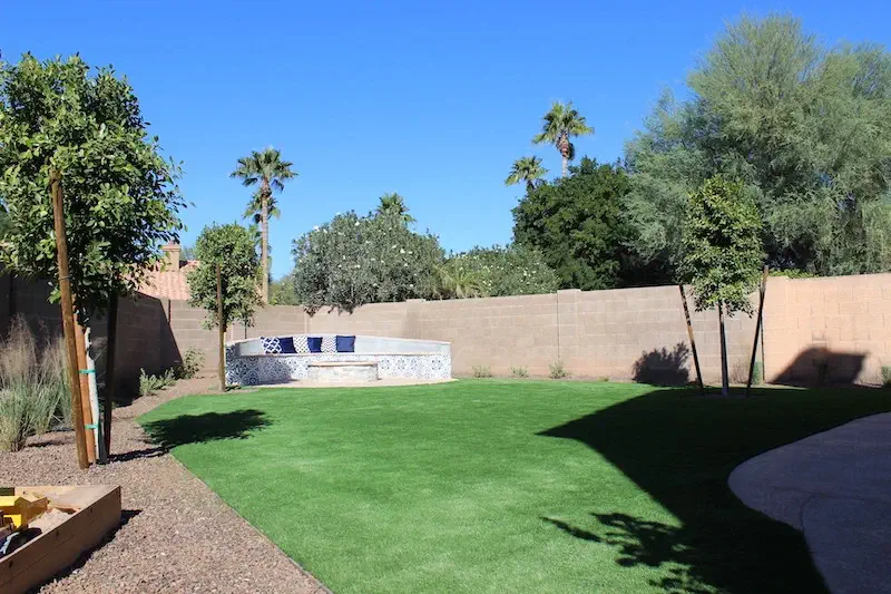 view of newly landscaped backyard with turf, fire pit, and plants